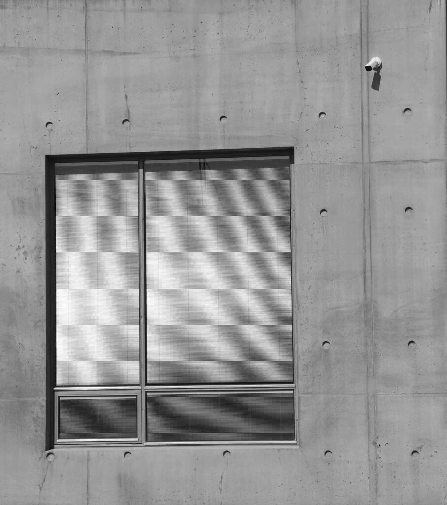 Modern concrete building with a large window and a security camera mounted on the wall